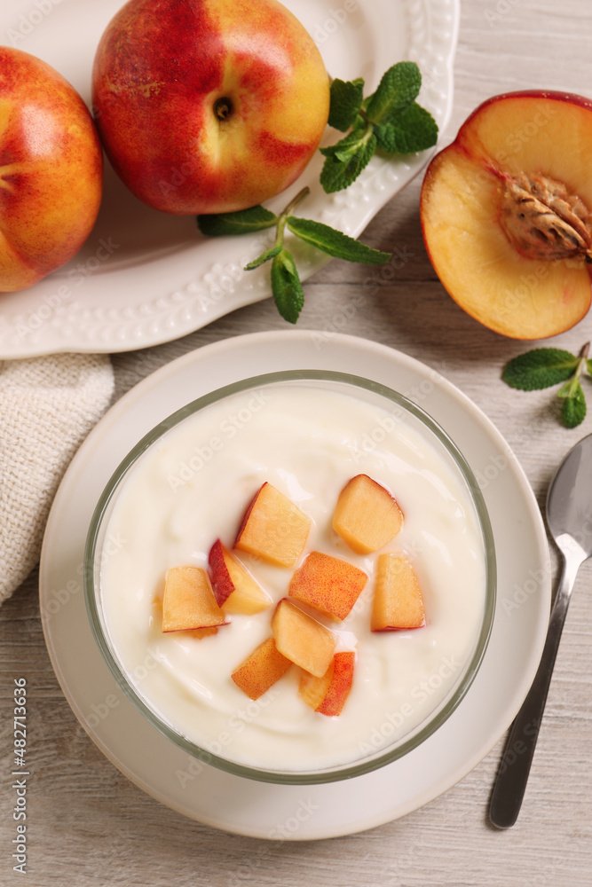 Delicious yogurt with fresh peach on light wooden table, flat lay Delicious yogurt with fresh peach on light wooden table, flat lay