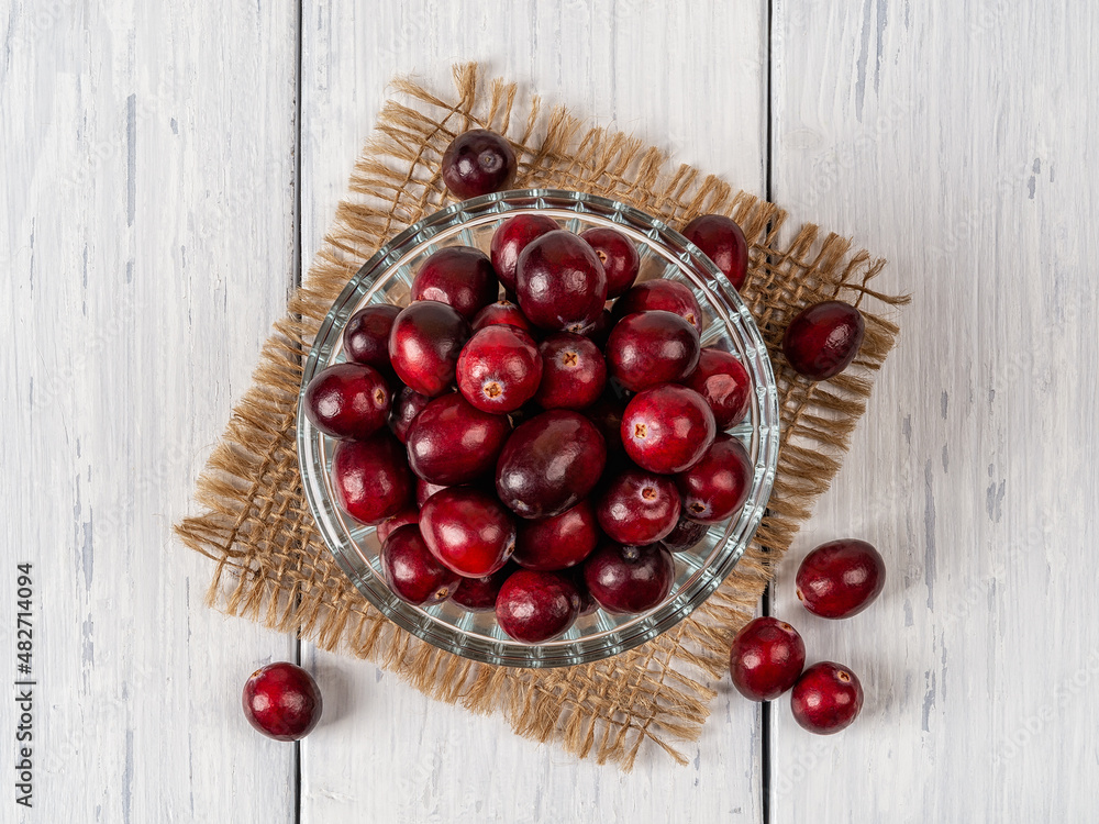 Top view of red ripe cranberries in a glass bowl on a white wooden table. Fresh wild berries for desserts, Thanksgiving and Christmas dishes. Superfood, antioxidant and vitamin healthy eating. Top view of red ripe cranberries in a glass bowl on a white wooden table. Fresh wild berries for desserts, Thanksgiving and Christmas dishes. Superfood, antioxidant and vitamin healthy eating.
