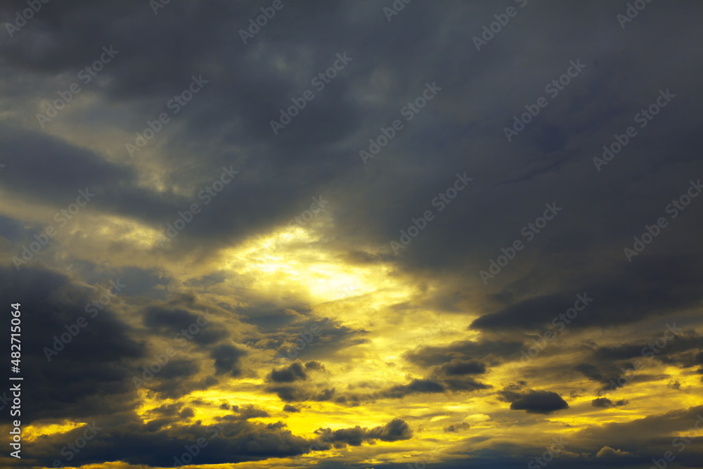 Dark clouds with yellow sunset . Fantastic twilight . Black and yellow heaven 