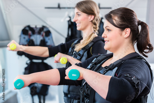 Two women friends exercising together for fitness in wireless ems center