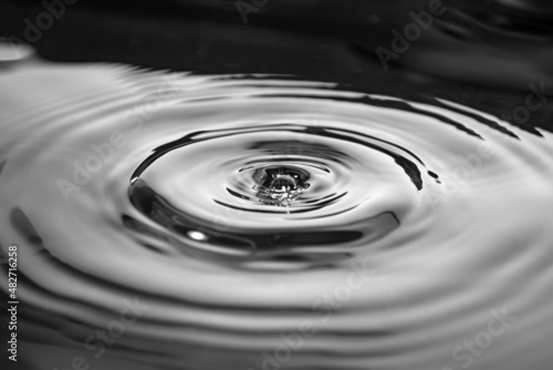 Wavy circles on the water with glare. Black and white photo.