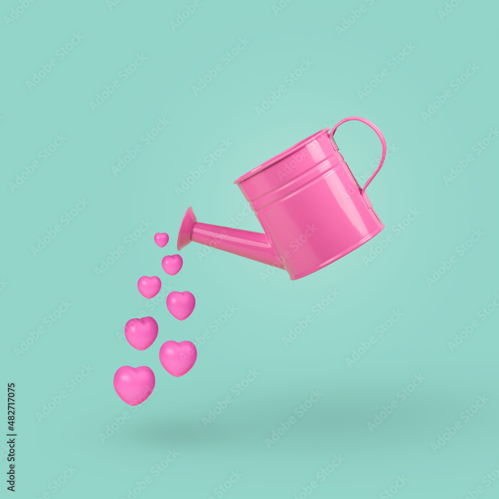 Obraz premium Watering can pouring pastel pink hearts isolated on a turquoise background. Valentines Day concept.