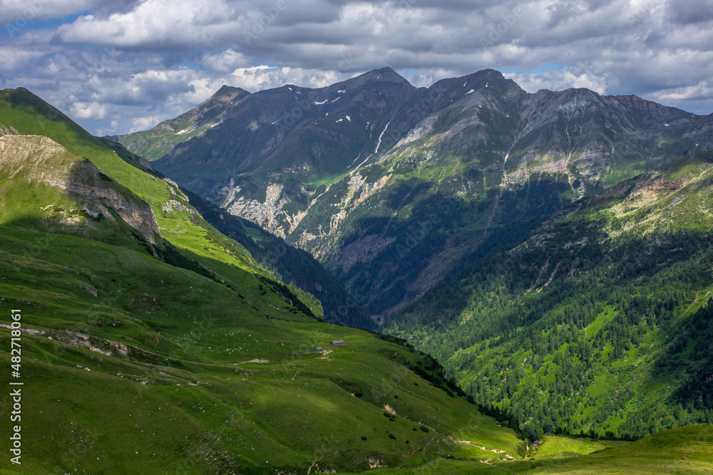 Austrian Alps. Mount Grossglockner. Highlands in summer. High mountains in the shadow of clouds and the rays of the sun. Mountain landscape. Juicy greens. Cloudy sky.