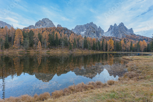 The Cadini di Misurina peaks and autumn colored woods reflecting on Lake Antorno, Dolomites, Italy