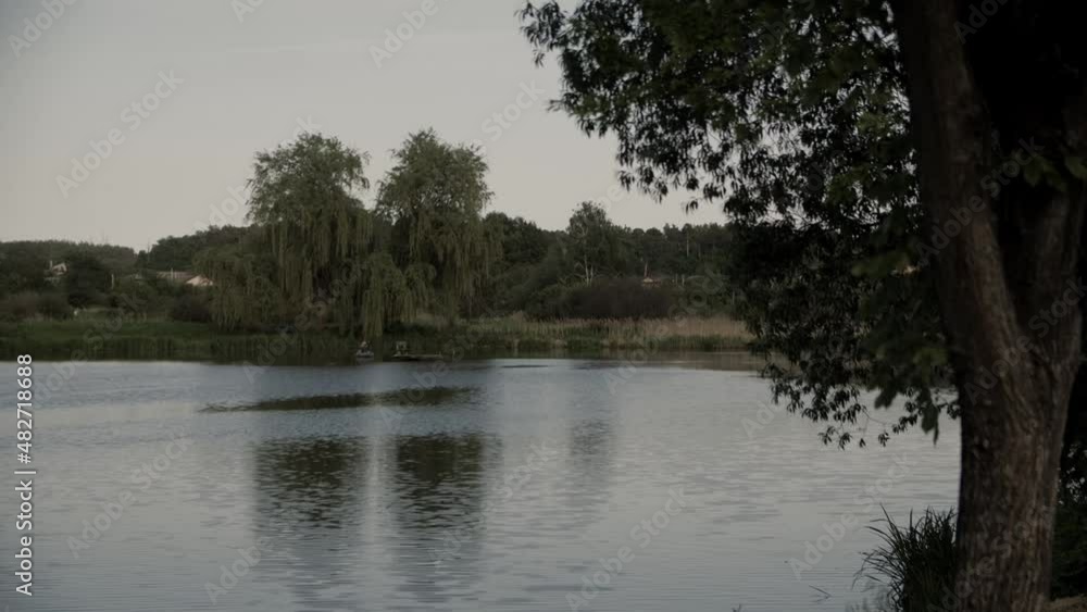 Lake view. Distant silhouette of fishermen. Fishermen are fishing on the lake. Lake view. Distant silhouette of fishermen. Fishermen are fishing on the lake.