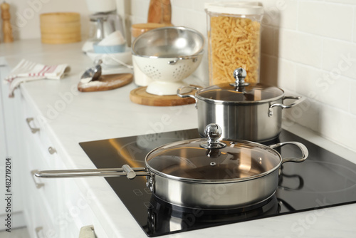 Pot and pan on electric stove in kitchen. Cooking utensils