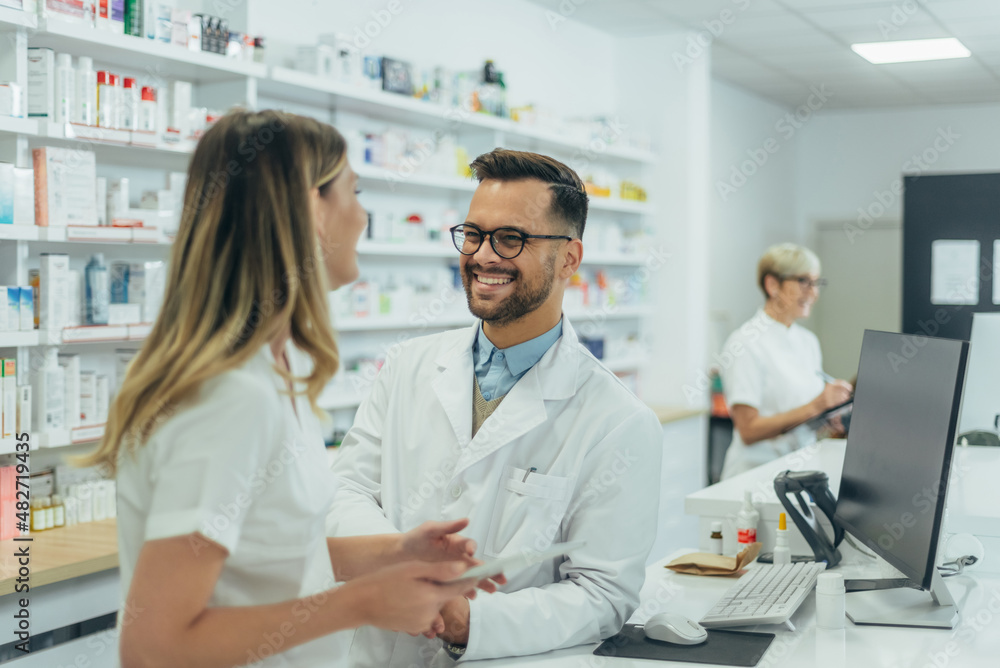 Male pharmacist working with young female colleague in a pharmacy Male pharmacist working with young female colleague in a pharmacy