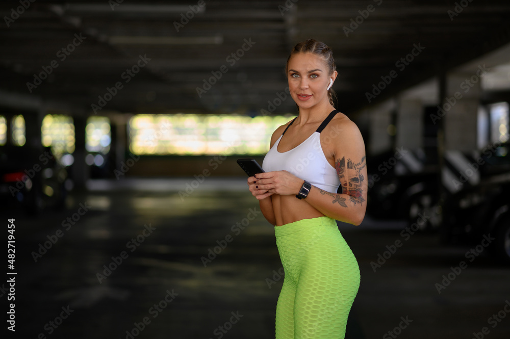 Fototapeta premium Woman using smartphone and airpods after finishing her training outside