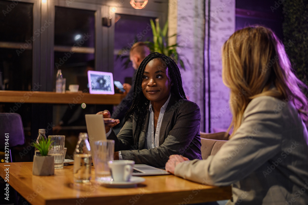 Two businesswoman having a meeting in a cafe while using a laptop Two businesswoman having a meeting in a cafe while using a laptop