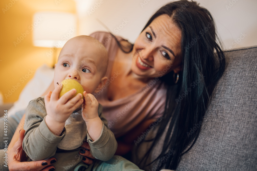Happy mother and baby eating fresh fruit at home Happy mother and baby eating fresh fruit at home