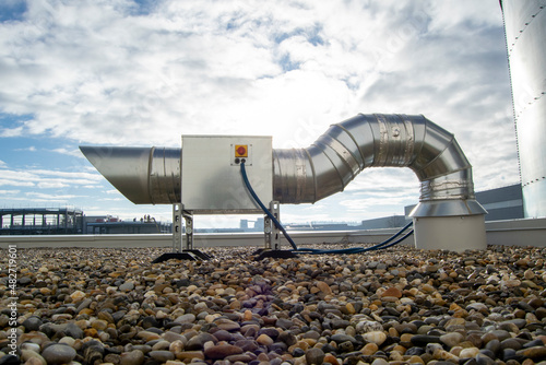 Air extractor and large galvanized steel pipes on the roof of a warehouse photo