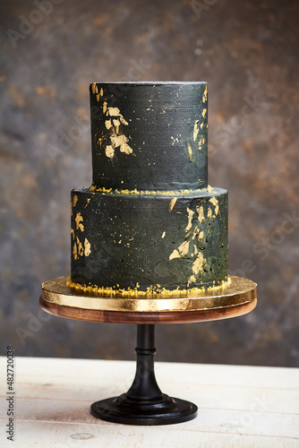 elegant black and gold wedding cake with a modern and luxurious boho look on a wood base