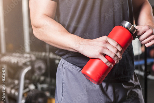 Muscular man holds red water bottle