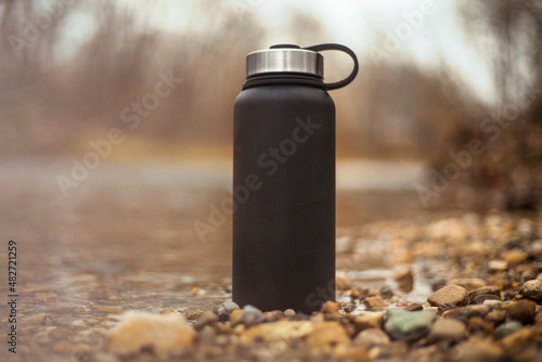 Black water bottle thermos in nature photo