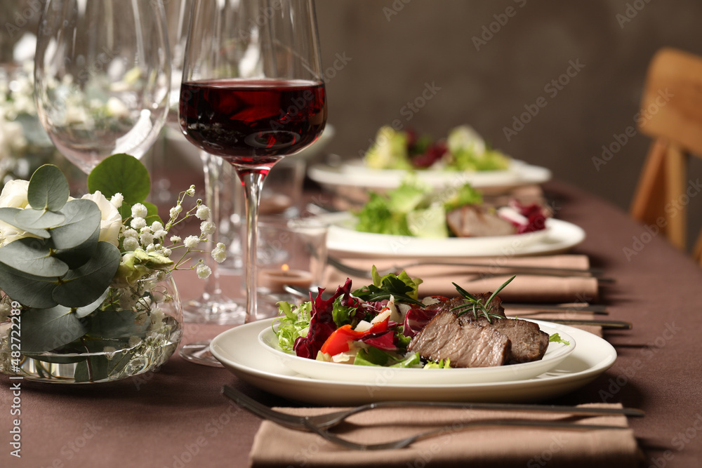 Delicious grilled meat with vegetables and wine served on table in restaurant