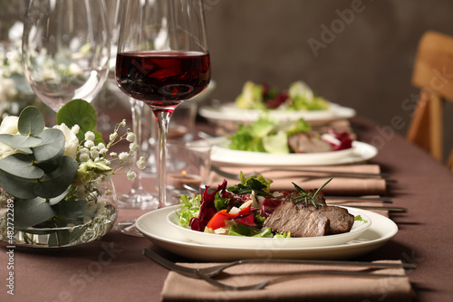 Delicious grilled meat with vegetables and wine served on table in restaurant