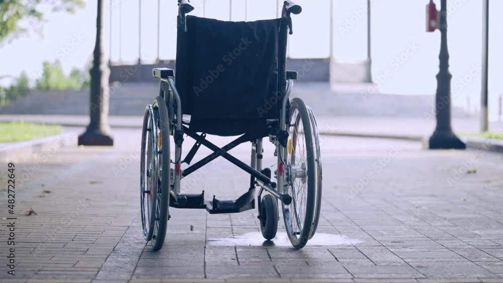 Empty wheelchair in city park, recovery from injury, successful rehabilitation Empty wheelchair in city park, recovery from injury, successful rehabilitation