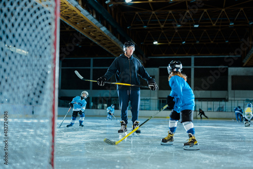 Little boy playing ice hockey with trainer