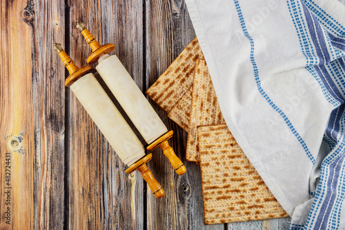 Matzah, tallit and torah on wooden background.