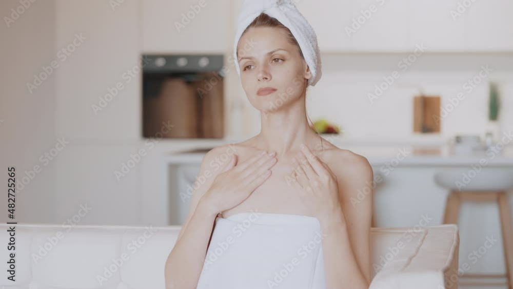 young female holding moisturizing cream wrapped in towel sitting on the couch spa and wellness at home or hotel young female holding moisturizing cream wrapped in towel sitting on the couch spa and wellness at home or hotel