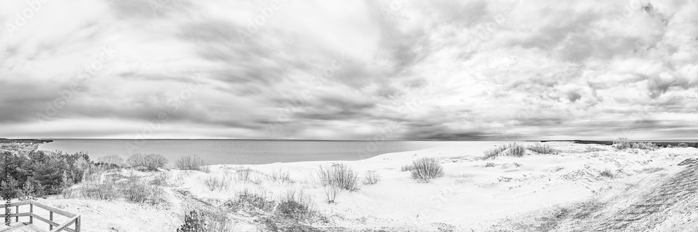 Sand dunes of the Curonian Spit in the cloudy weather with the sky covered with clouds on the shore of the Curonian Bay