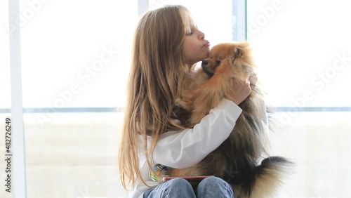 Little cute child girl at home play and hug holding her small pet dog at home