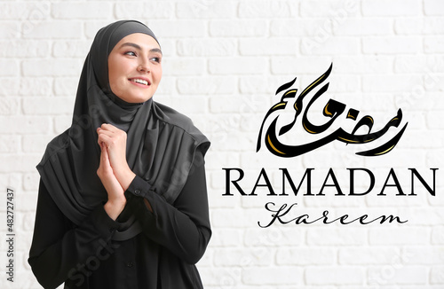 Young Muslim woman on white brick background. Ramadan celebration photo