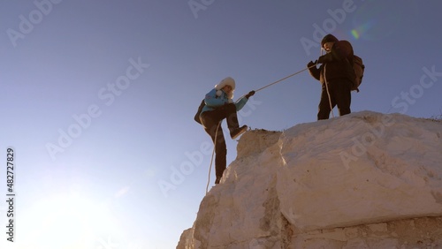 Woman Climber climb the mountain on a rope.Teamwork of business people. Travelers climb one by one up the rock. Help in difficult circumstances. The team of businessmen will win.