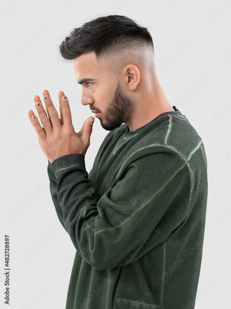 Young concentrated man with stylish manicure on light background Young concentrated man with stylish manicure on light background