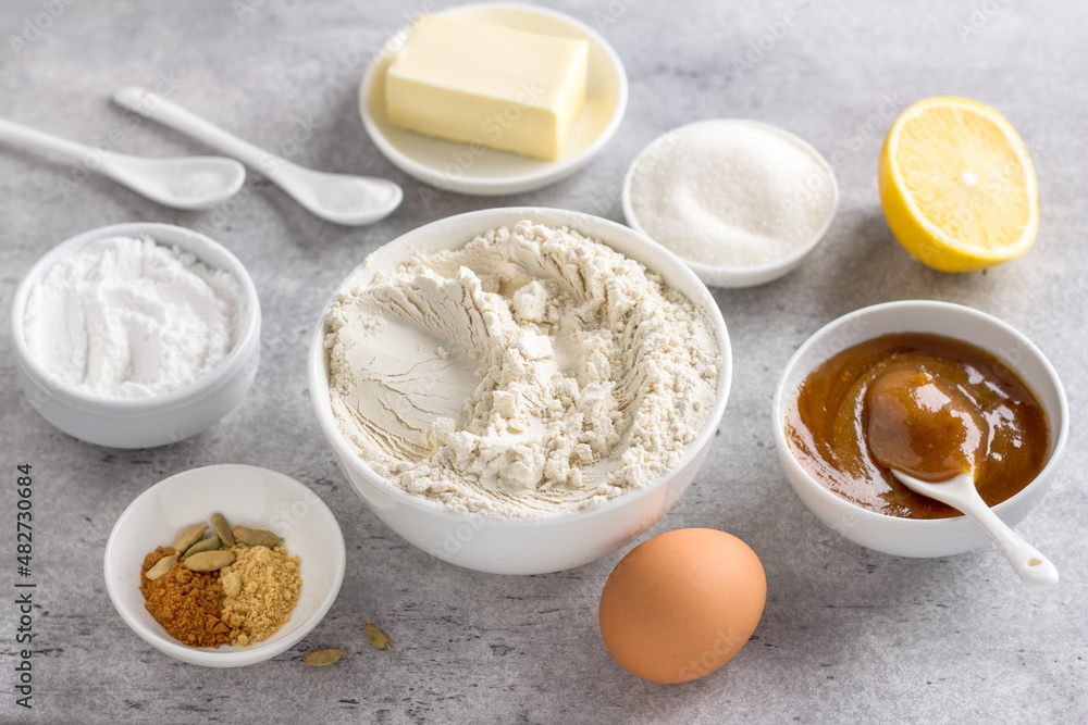 Ingredients for making steamed honey gingerbread: wheat flour, honey, egg, butter, sugar, powdered sugar, lemon, baking powder, spices, on a gray background, top view Ingredients for making steamed honey gingerbread: wheat flour, honey, egg, butter, sugar, powdered sugar, lemon, baking powder, spices, on a gray background, top view