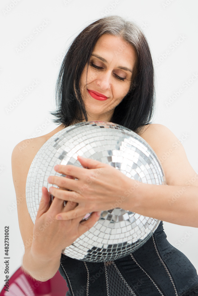 Studio photo of middle aged woman starting getting grey-haired wearing black clothes with silver disco ball in hands on white background, middle age sexy lady, happy life concept Studio photo of middle aged woman starting getting grey-haired wearing black clothes with silver disco ball in hands on white background, middle age sexy lady, happy life concept