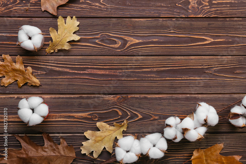 Cotton flowers and autumn leaves on wooden background