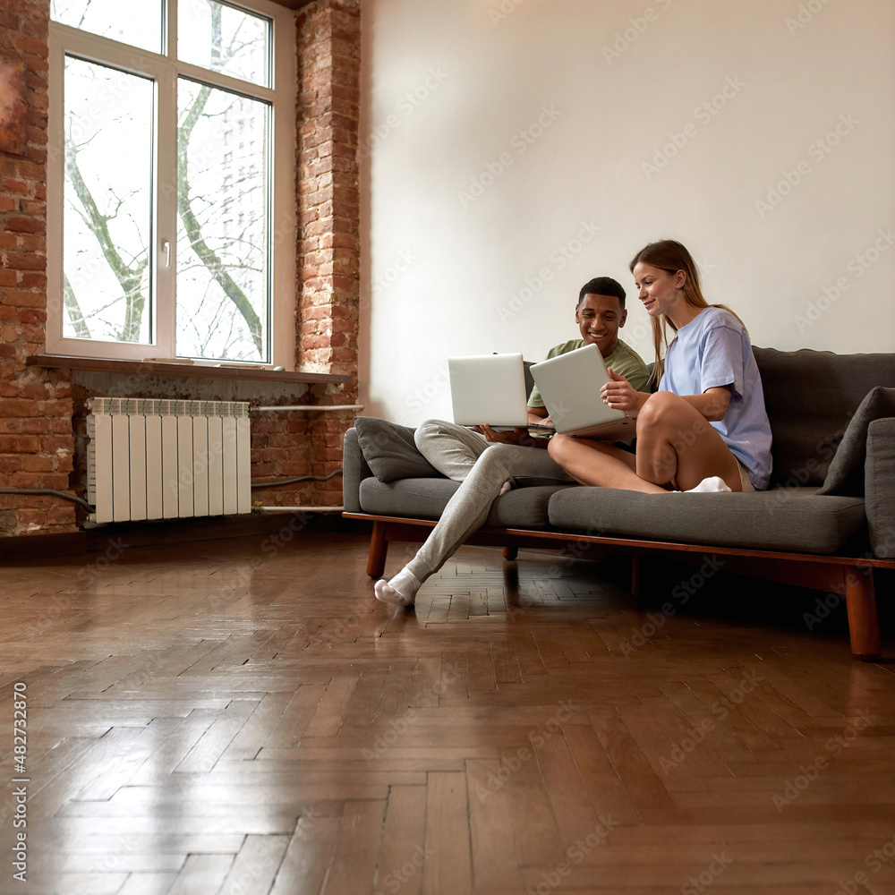 Multiethnic couple looking on laptop of each other Multiethnic couple looking on laptop of each other