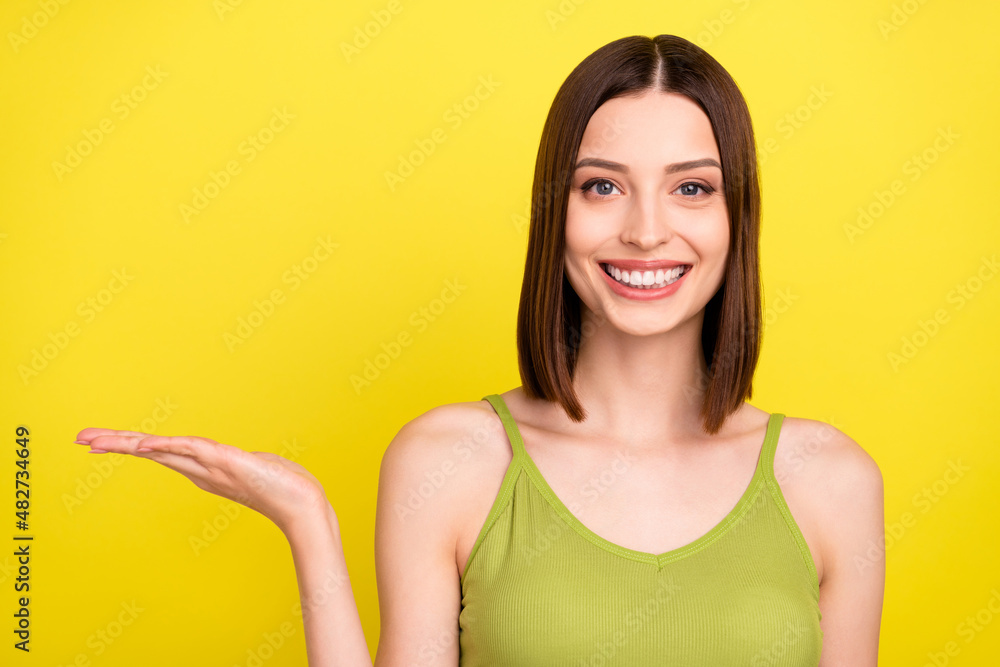 Photo of sweet brunette millennial lady hold empty space wear green top jeans isolated on yellow color background Photo of sweet brunette millennial lady hold empty space wear green top jeans isolated on yellow color background