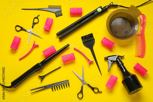 Set of hairdresser tools and hair curlers on color background