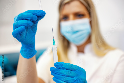 Vaccine, prevention, and immunization. Close up of a nurse in the laboratory holding a syringe and preparing it for a patient.