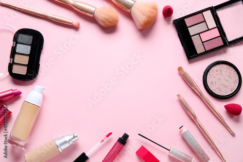 Frame made of different makeup products on pink background