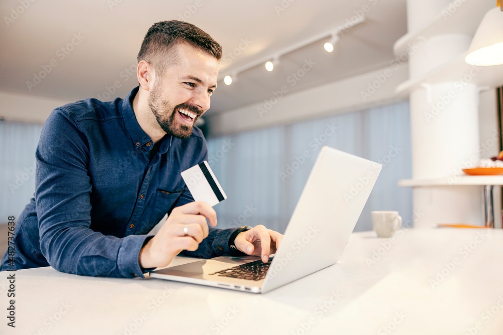 A happy man booking, shopping online and paying bills on the laptop from his comfortable home. A happy man booking, shopping online and paying bills on the laptop from his comfortable home.