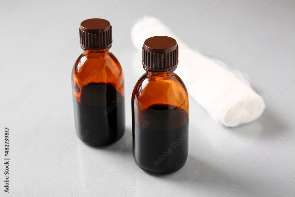 Bottles with iodine and gauze roll on grey background, closeup Bottles with iodine and gauze roll on grey background, closeup
