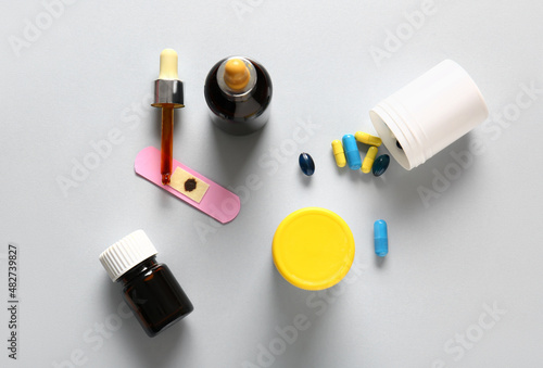 Bottles with iodine, medical plaster and pills on grey background