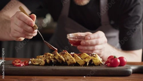 Professional Chef serving chicken breast with salt, meat grill steak with spices, work in a busy kitchen getting ready for service. 