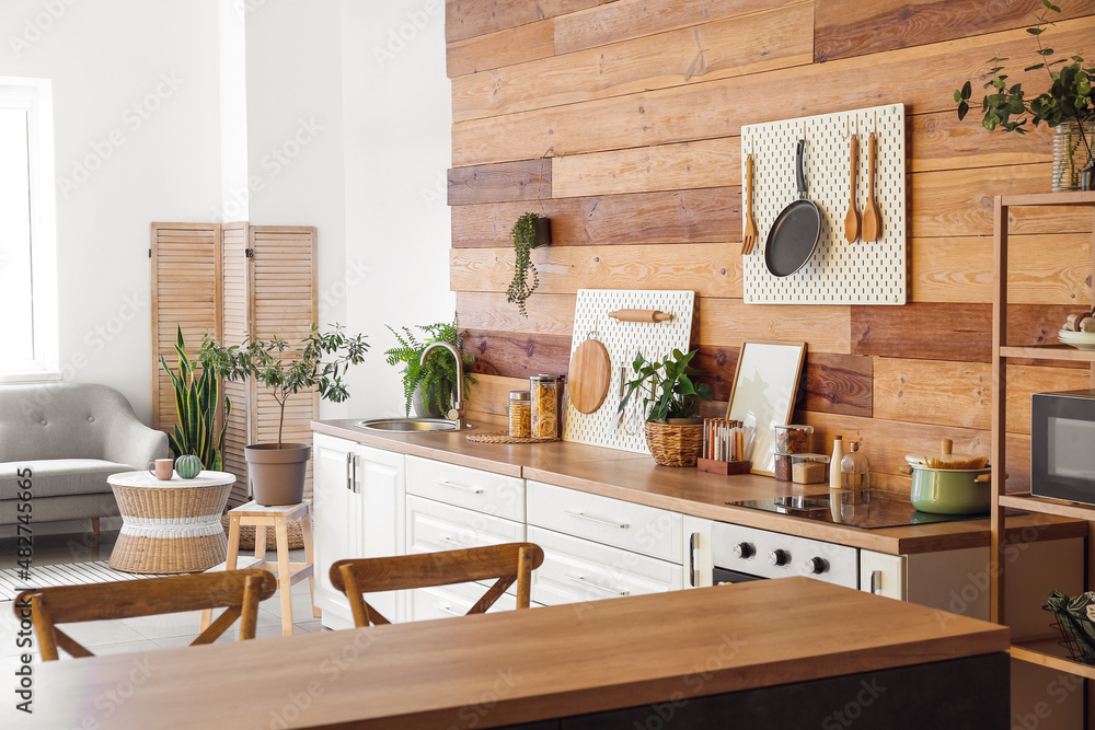 Interior of modern kitchen with white counters, peg boards and wooden wall - obrazy, fototapety, plakaty 