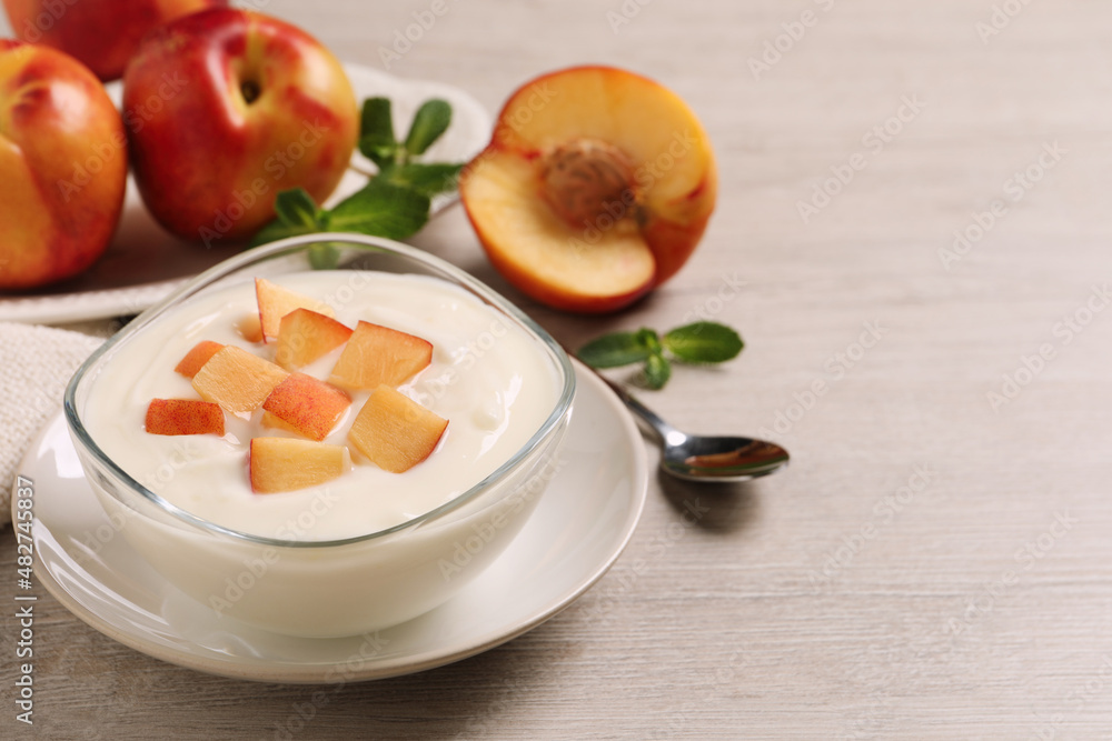 Delicious yogurt with fresh peach on light wooden table, space for text Delicious yogurt with fresh peach on light wooden table, space for text