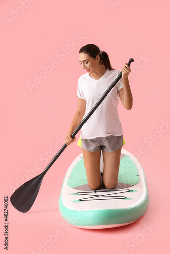 Photography Young woman with board for sup surfing and oar on color background