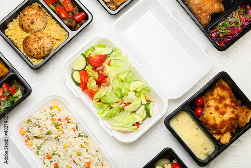 Different lunch boxes with delicious meals on light background