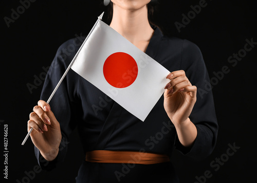 Beautiful young woman with flag of Japan on black background photo