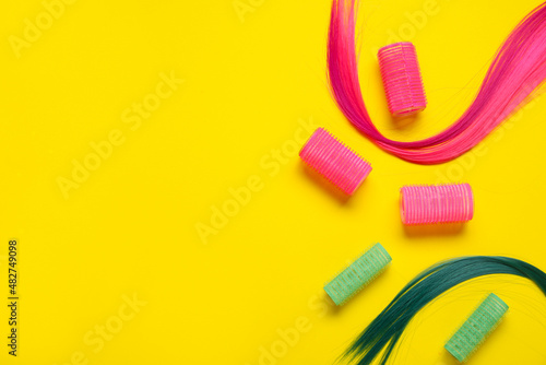Strands of hair with curlers on color background