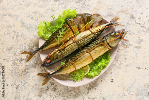 Plate with smoked mackerel fishes on beige background