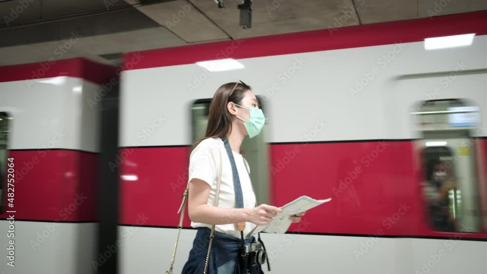 Beautiful Asian female tourist with face mask, eyeglasses, and camera, searching traveler location map, looking for destination at train station in Thailand, railway transportation, casual lifestyle. Beautiful Asian female tourist with face mask, eyeglasses, and camera, searching traveler location map, looking for destination at train station in Thailand, railway transportation, casual lifestyle.