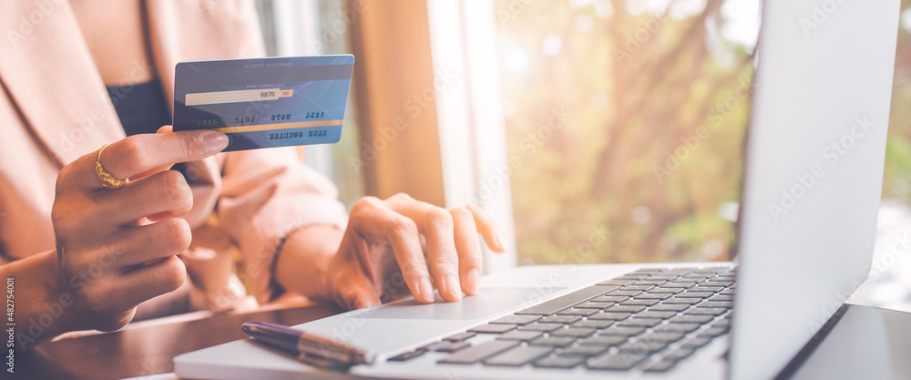 Woman holding credit card and searching online with computer.